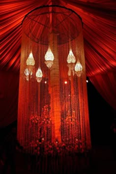 an elaborate chandelier is lit up at night with red drapes and hanging lights