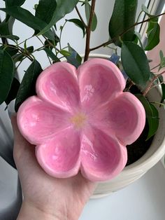 a hand holding a pink flower shaped planter