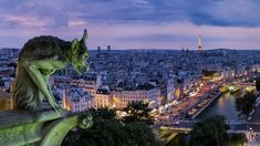 a gargoyle statue overlooking the city of paris