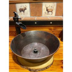 a large metal bowl sink sitting on top of a wooden counter next to a faucet