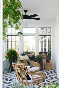 a room that has some plants on the floor and a ceiling fan in front of it