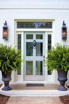 two large planters with plants in front of a door