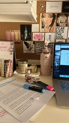 an open laptop computer sitting on top of a desk next to a pile of papers