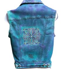 the back of a blue jeanie jacket with an embroidered flower design on the front