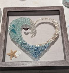 a shadow frame with some beads in the shape of a heart and a starfish