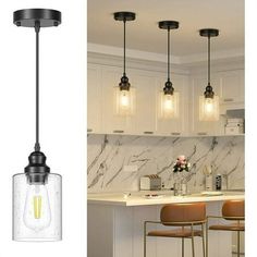 three lights hanging over a kitchen counter next to a bar with stools in it