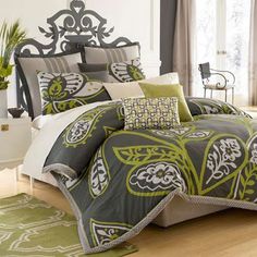 a bed with green and white comforters on top of it in a room next to a window