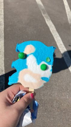 a hand holding up a blue and white piece of paper with green eyes on it