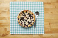 a blue and white checkered table cloth with a pie on it next to a spoon