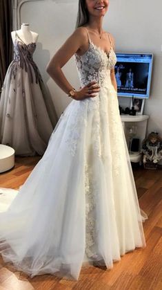 a woman in a wedding dress standing next to a mannequin on a wooden floor