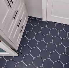 a bathroom with hexagonal tiles on the floor and cabinetry in the corner