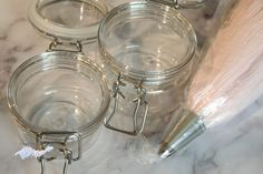 three glass jars with metal handles on a marble counter