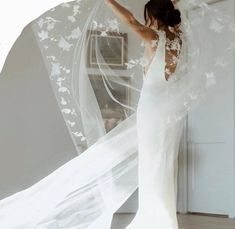 a woman in a white wedding dress is holding her arms out and looking at the ceiling