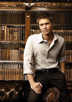 a man sitting on a couch in front of a bookshelf