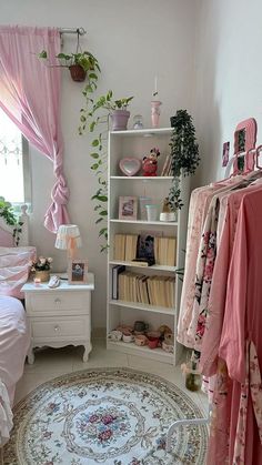 a bedroom with pink curtains, bedding and rugs on the floor in front of a window