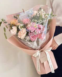 a woman holding a bouquet of flowers with the words happy birthday written on it in white lettering