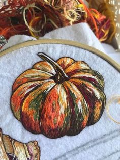 a close up of a pumpkin on a piece of cloth next to some yarn and scissors