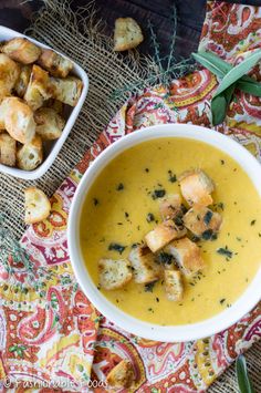 two bowls filled with soup and croutons on top of a table