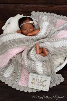 a newborn baby wrapped in a blanket with the words welcome to the world on it