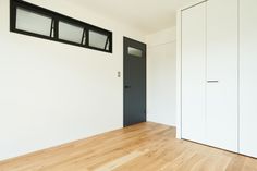 an empty room with white walls and wooden floors, black framed windows on the wall