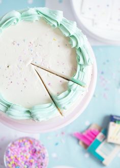 a white cake with sprinkles and two slices taken out of it on a table