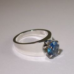 "This ring is a very classic design! The two sides come up to a peak that holds a beautiful Blue zircon. Blue zircon is a beautiful rich blue color which reminds me of the ocean! It is also one of the birthstones for the month of December. I can make this ring for you with any other birthstone...convo me for details. This zircon is a \"laboratory grown\" type of spinel. I first cast this mounting using the lost wax process, then silver solder a 4 prong head into place to hold this 8mm stone. The Blue Zircon Ring, Zircon Ring, Ring Blue, Blue Zircon, Blue Band, Lost Wax, Blue Rings, Ring Sterling Silver, Sterling Ring