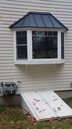 an air conditioner sitting in front of a window on the side of a house