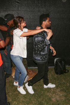 two people are dancing in the grass with other people behind them and one person is wearing white shoes