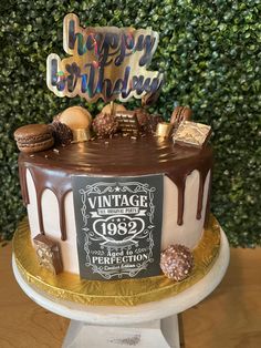 a birthday cake with chocolate icing and candies on top, sitting on a table