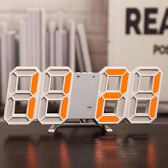 an orange and white alarm clock sitting on top of a table