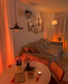 a living room filled with furniture next to a window covered in curtains and hanging lights