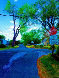 a stop sign on the corner of a street with trees and houses in the background