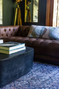 two books are sitting on top of a coffee table in front of a brown couch