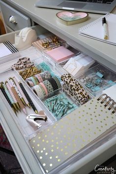 an organized drawer with pens, notebooks, and other office supplies on the desk