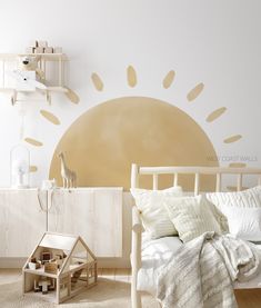 a white bed sitting next to a wall with a sun painted on it's side