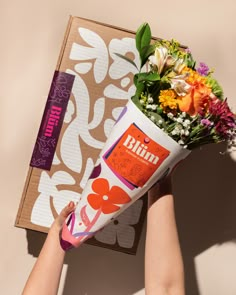 a person holding a bouquet of flowers in front of a box with the word bunn on it