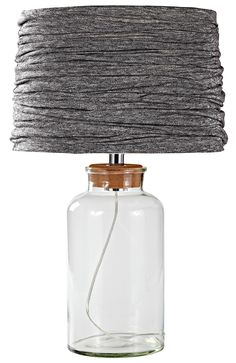 a glass lamp with a wooden base and grey fabric shade on the top of it