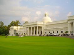 a large white building sitting on top of a lush green field