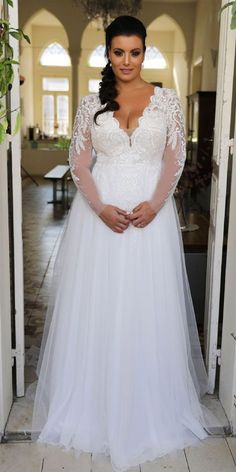 a woman in a white wedding dress is posing for the camera with her hands on her hips