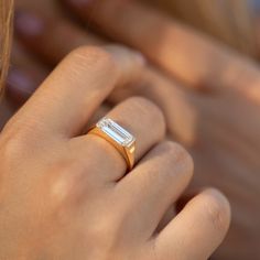 a close up of a person wearing a ring with a baguette on it