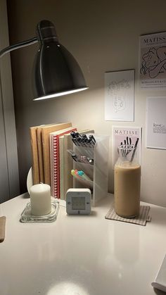 a desk with a lamp, books and an alarm clock on it's side