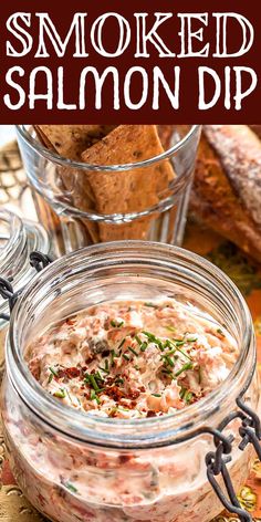 a glass jar filled with smoked salmon dip on top of a table next to bread