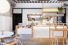 the interior of a restaurant with wooden tables and chairs, an open kitchen area on one side