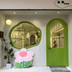 there is a green door with a flower on it and a mirror in the wall