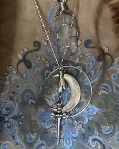 a silver necklace with a crescent and a cross on it