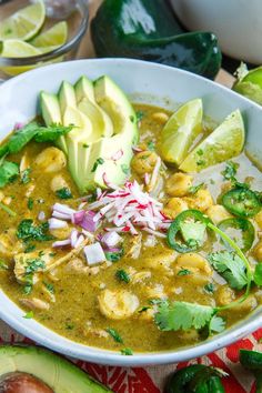 a white bowl filled with soup next to sliced avocados and cilantro