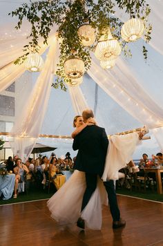 a bride and groom dance together on the dance floor at their wedding reception in an outdoor tent