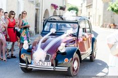 a wedding car is parked on the side of the road with people looking at it