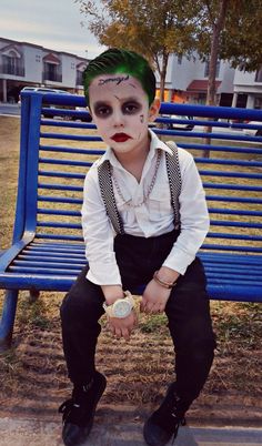 a person with green hair and makeup sitting on a bench