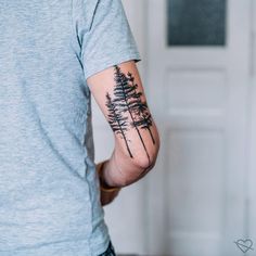 a man with a pine tree tattoo on his left arm and right arm behind him